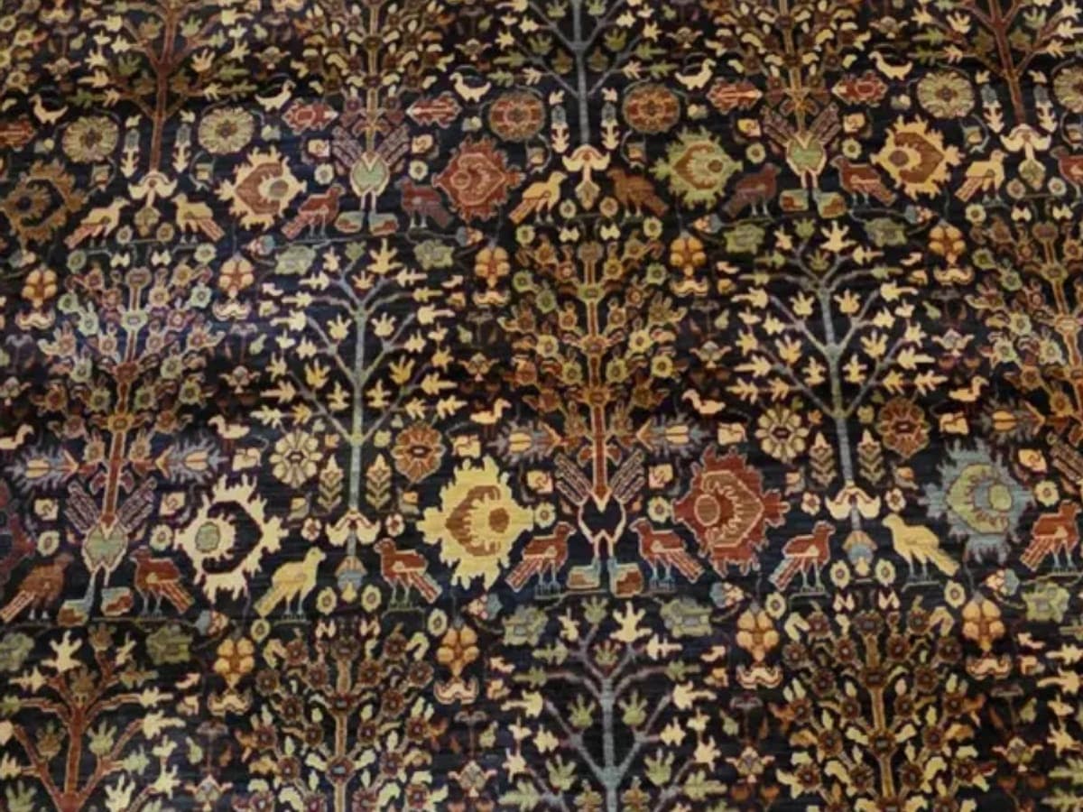 Detail of a deep indigo Persian rug after cleaning, its tree of life pattern with birds and flowering branches readable knot by knot