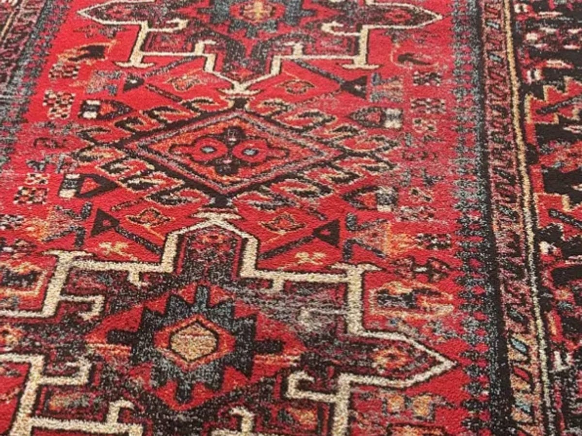 Red tribal rug after low moisture cleaning, its geometric medallions sharp against the dark border